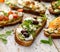 Open sandwich made of slices of sourdough bread with avocado, feta cheese, kalamata olives, olive oil and oregano on a wooden whit