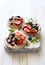 Open sandwiches with cream cheese, strawberries, blueberries, jam and almond flakes close up