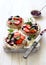 Open sandwiches with cream cheese, strawberries, blueberries, jam and almond flakes close up