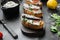 Open sandwiches with toast bread ricotta and fish sardines, on black dark stone table background