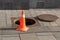 Open sewer manhole cover and traffic cone on a city street. Sewerage repair. Emergency service and accident. Drainage system