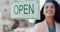 Open sign, business and woman manager by welcome poster on store window, happy entrepreneur and startup. Creative