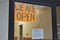 We Are Open sign entrance door with new pandemic regulations posted