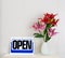 Open sign hang on shelf in store with red lily