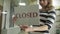 Open sign is turned to closed in a storefront window. woman flipping nameplate with open sign