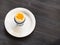 Open soft-boiled white egg in cup on plate on dark