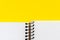 Open spiral notebook with blank empty white sheets in the bottom of a bright yellow background