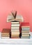 Open stacking book, hardback colorful books on wooden table, red, pink background. Back to school. Copy space for text