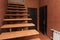 Open staircase with stone steps going up to the inside corridor rooms close-up on a background of bright walls and dark doors