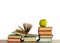Open textbook, pile of books in colorful covers and green apple on wooden table with white background. Distance home education.