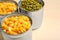 Open tin cans of sweet corn and peas on table, closeup