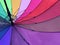 An open umbrella is bright, multi-colored, close-up. Background texture: umbrella mechanism. Large rain umbrella, all colors of