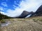 An open valley of rocks and creeks leading towards the teal waters of Berg Lake