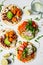 Open vegan tortilla wraps with sweet potato, beans, avocado, tomatoes, pumpkin and  sprouts on white background, flat lay. Healthy