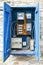 Open vintage blue wooden electrical control cabinet with electricity meters and fuses