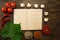 Open vintage book with berries, tomatoes, Chile peppers, spices and grape leaf on wooden background. Healthy vegetarian food.