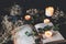 Open vintage poetry book on a black table surface with white lit burning candles and dried flowers