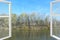 Open window overlooking river and trees. View of the forest and river in autumn