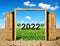 Open wooden door to the beautiful spring landscape with number 2022. Concept of Happy New Year.