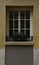 Open wooden window in an old house with yellow walls. On the windowsill there is a blooming heather, from the street side.