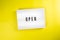 Open word on lightbox on yellow background isolated