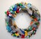 Open wreath decorated with colorful plastic bottles on a white background