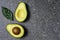 Opened avocado showing seed on textured stone background