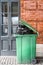 Opened big green plastic trash can with full trash bags. Disposal of waste