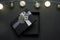 Opened black gift box with silver ribbon. Gift on a black granite surface. Christmas lights above the box