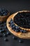 Opened blueberry tart on a wooden stand next to fresh blueberries