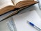 Opened books and notebooks are on the table. A pen lies on a blank sheet of a notebook. Background for education, scientific work