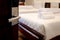 Opened door with blurred background of stack of fresh white bath towels on white bed in hotel room, travel and convenient