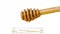 Opened honey jar with detail of wooden honey dipper on top with drop honey