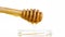 Opened honey jar with detail of wooden honey dipper on top with drop honey