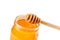 Opened honey jar on white background with wooden honey dipper on top pouring honey