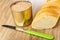 Opened jar with liver pate, piece of baguette, knife on wooden table