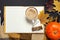 Opened notebook, pumpkin, cup of pumpkin cocoa or coffee, cinnamon, yellow autumn maple leaf, checkered plaid on black background