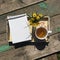 Opened notepad, cup of tea and small bouquet of wild flowers on a tray on a old wooden background.