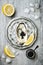 Opened oyster with black sturgeon caviar and lemon on ice in metal plate on grey concrete background. Top view, flat lay