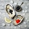 Opened oysters with red salmon and black sturgeon caviar and lemon on ice on grey concrete background. Top view, flat lay