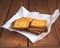 Opened pack of cookies on brown paper lying on a wooden tray