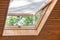 Opened roof window with blinds or curtain in wooden house attic. Room with slanted ceiling made of natural eco materials