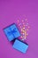 Opened shiny classic blue gift box with satin bow and magic confetti in the shape of stars as attributes of party