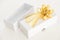 Opened square white gift box with golden ribbon, on white background