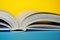 An opened thick book or diary on a yellow and blue background. College or school library. Close-up