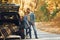 Opened trunk. Couple standing on the road in park near automobile