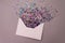 Opened white envelope with multicolored sparkle glitter confetti letters on pastel lilac background. Festive greeting concept.