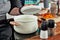 Opened white saucepan with wood pens on the black stove and glass spice mill in the kitchen room. Cooking a soup, preparation.