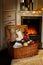 Opened wicker box with Christmas decoration is next to fake fireplace