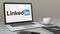 Opening laptop with LinkedIn logo on the screen. Modern workplace conceptual editorial 4K clip